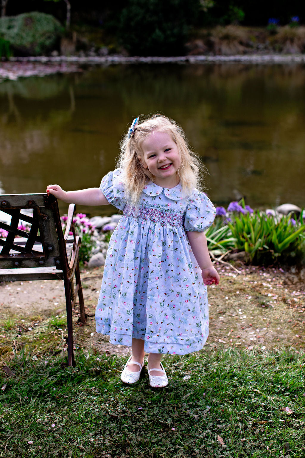 “Rosebud hand-smocked vintage-inspired girls' dress by Vanessa Lynne, featuring delicate pastel embroidery, soft fabric, and intricate floral detailing, perfect for special occasions.”