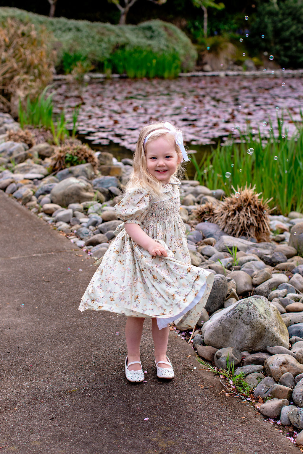 “Adelaide hand-smocked 100% cotton girls’ party dress by Vanessa Lynne, featuring embroidered roses, puff sleeves, and ties at the back, fully lined with white cotton. A timeless classic, made in New Zealand.”